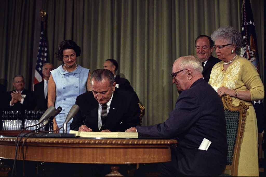 President Lyndon Johnson signs Medicare Bill into law as former President Harry Truman watches